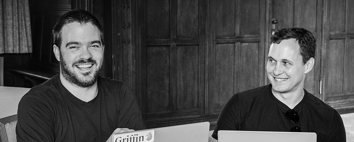 Two founders smiling beside a laptop